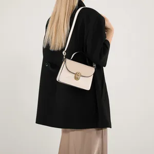 Piccola borsa a tracolla beige minimalista con chiusura girevole dorata e manico nero