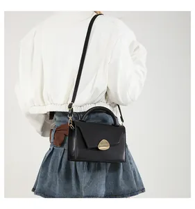 Minimalist black leather mini crossbody bag with gold sculptural lock on a model
