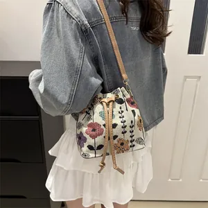 Ethnic style drawstring bucket bag with floral jacquard weave and brown shoulder strap