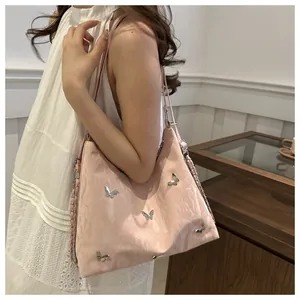 Detail of pink faux leather tote bag with silver butterfly charms and chain accents
