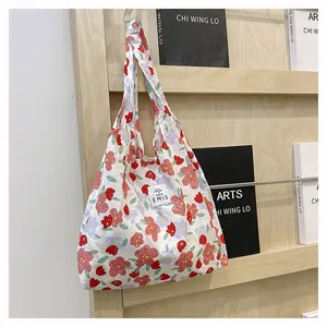 Détail du sac cabas EMIS en toile fleurie avec étiquette tissée sur support en bois