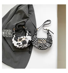Detail of half-moon underarm bags with cow and zebra patterns and golden metal buckles