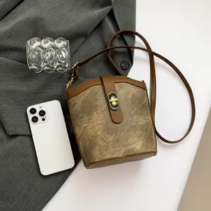 Detail of vintage canvas bucket bag with brown leather trim and golden twist lock closure