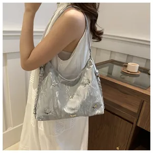 Close-up of a silver metallic hobo bag featuring 3D butterfly charms and ruched texture