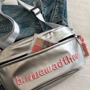 Detail of silver metallic crossbody bag showing a zipper pocket and its storage capacity