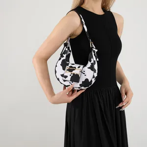 Stylish black and white cow print hobo bag with a gold metal clasp for modern women