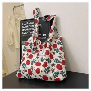 Détail du sac cabas en toile avec motifs de roses rouges et étiquette de marque tissée