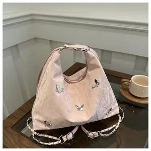 Detail of light pink pleated handbag featuring 3D silver butterflies and chain strap