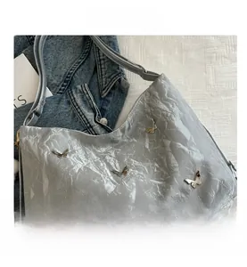 Detail shot of silver pleated tote bag featuring shiny metallic butterfly embellishments