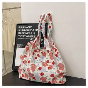 Vue détaillée du sac cabas en toile avec imprimé fleuri et étiquette logo EMIS