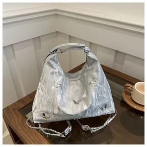 Detailed macro view of metallic silver bag with 3D metal butterflies and chain strap