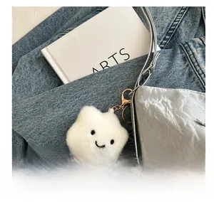 Close-up of white plush cloud charm with a smiling face on a stylish shoulder bag