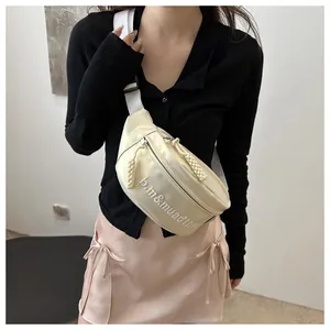Dettaglio della borsa a tracolla crema con ricamo, tracolla larga e tirazip in corda