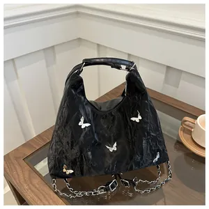 Detail of black pleated bag with silver butterfly accents and leather chain strap