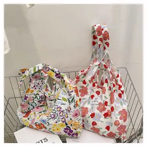 Détail de sacs fourre-tout en toile florale avec motifs roses et logo EMIS dans un panier