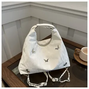 Close-up of white pleated handbag featuring silver butterfly charms and chain strap detail