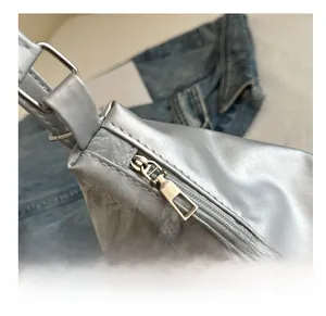 Detail of a smooth silver metal zipper and butterfly buckle on a pleated silver bag