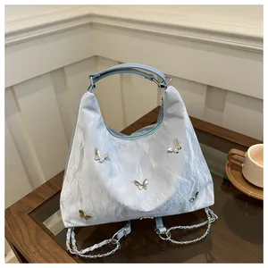 Detail of light blue bag featuring silver butterfly charms and crinkle texture fabric