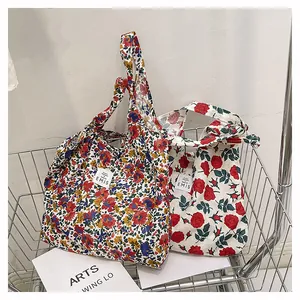 Détail de sacs fourre-tout en toile à motifs floraux et roses dans un chariot