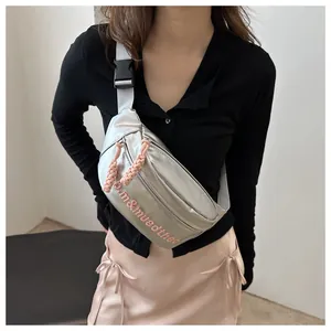 Dettaglio borsa a tracolla argento con ricamo rosa e tiranti della zip intrecciati