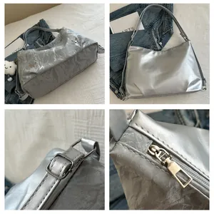 Detail view of silver crossbody bag with metallic finish and butterfly hardware accents