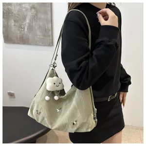 Detail of light green crescent bag with silver butterfly charms and plush cloud pendant