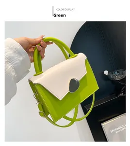 Close-up of green and cream contrast handbag featuring a sleek grey metal buckle