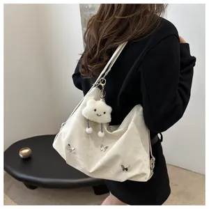 Detail of off-white large capacity tote bag with metal butterfly rivets and plush charm