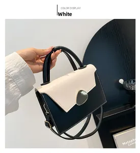 Close-up of contrast black and white shoulder bag with circular metal buckle and stitching