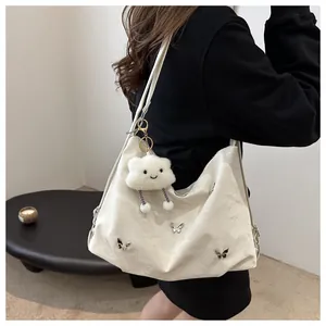 Detail of white large shoulder bag with silver butterflies and cloud plush charm decoration