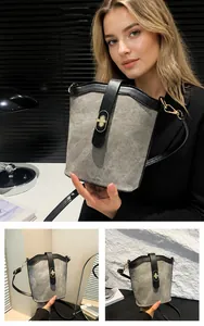 Detail of light gray canvas bucket bag with black leather trim and golden twist lock