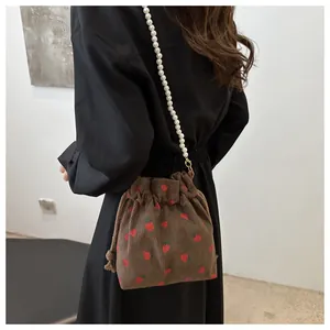 Détail du sac seau en velours à fraises avec bandoulière en perles blanches