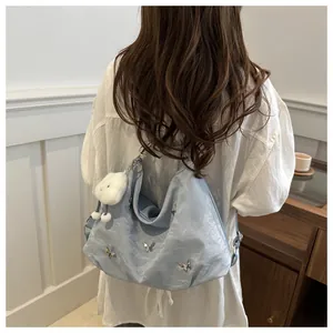 Close-up of light blue nylon tote bag featuring silver butterfly details and plush charm