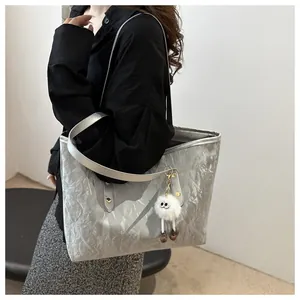 Detail of silver tote bag featuring unique wrinkled texture and a white plush charm
