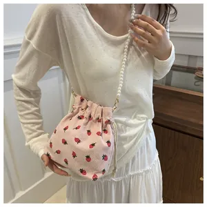 Détail du sac seau en velours côtelé rose avec imprimé fraise et bandoulière perle