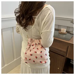 Détail du sac seau en velours rose avec imprimés fraises et bandoulière en perles chics