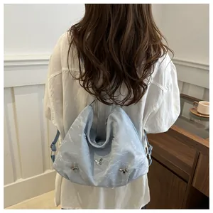 Detail of light blue pleated bag with silver butterfly charms and adjustable strap