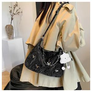 Dettaglio borsa tote nera plissettata con farfalle metalliche e ciondolo peluche