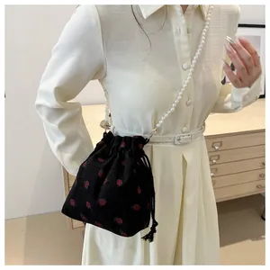 Détail du sac seau en velours noir à imprimé fraise avec bandoulière de perles