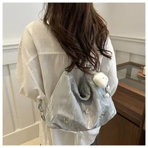 Silver metallic pleated tote bag with butterfly details and plush charm on a model