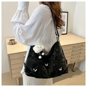 Detail of black pleated tote bag with silver butterfly charms and plush cloud pendant