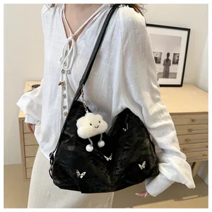 Detail of black velvet tote bag featuring silver butterfly patterns and a cloud plush charm