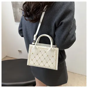 Sac à bandoulière blanc avec broderie cœur et bords ondulés porté par un modèle