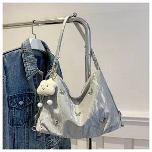 Close-up of silver tote bag featuring butterfly metal accents and a cloud plush charm