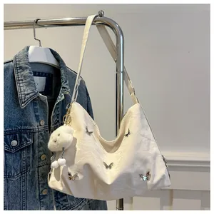 Detail of cream white leather bag with metal butterflies and plush cloud charm decor