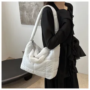 Detail of white quilted puffy shoulder bag featuring square stitching and padded strap