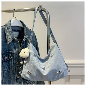 Detail of light blue hobo bag with butterfly ornament and plush cloud pendant charm