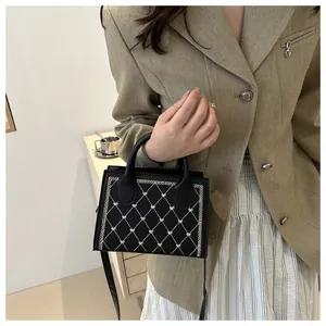 Détail d'un sac bandoulière en PU noir avec broderie matelassée en cœur et double poignée