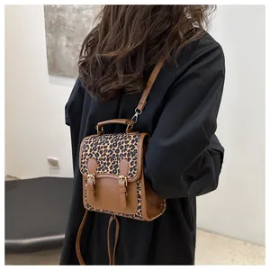 Rear view of a model wearing a small leopard print and brown leather backpack