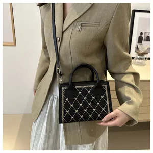 Détail du sac bandoulière noir avec broderie matelassée en forme de cœur et coutures